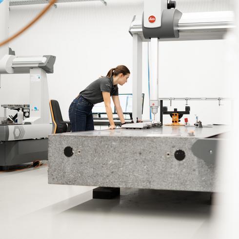 Messräume nach VDI/VDE 2627 Eine Frau lehnt sich an eine KMG und beobachtet die Vermessung eines Bauteils